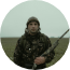 European hunter in camouflage clothing holding a rifle in an open field
